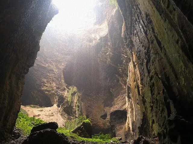 El interior de una enorme cueva con luz solar entrando por una abertura en el techo.