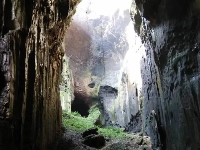 Vista interior de una gran cueva con una abertura al cielo.