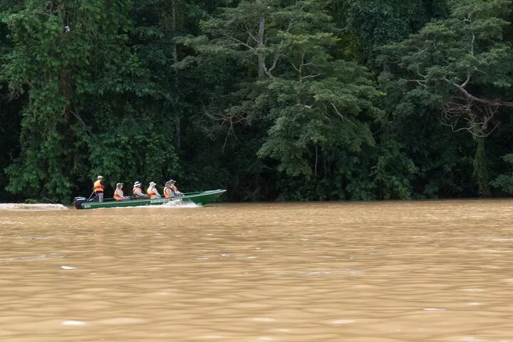 Una pequeña embarcación que lleva pasajeros por un río ancho y marrón.